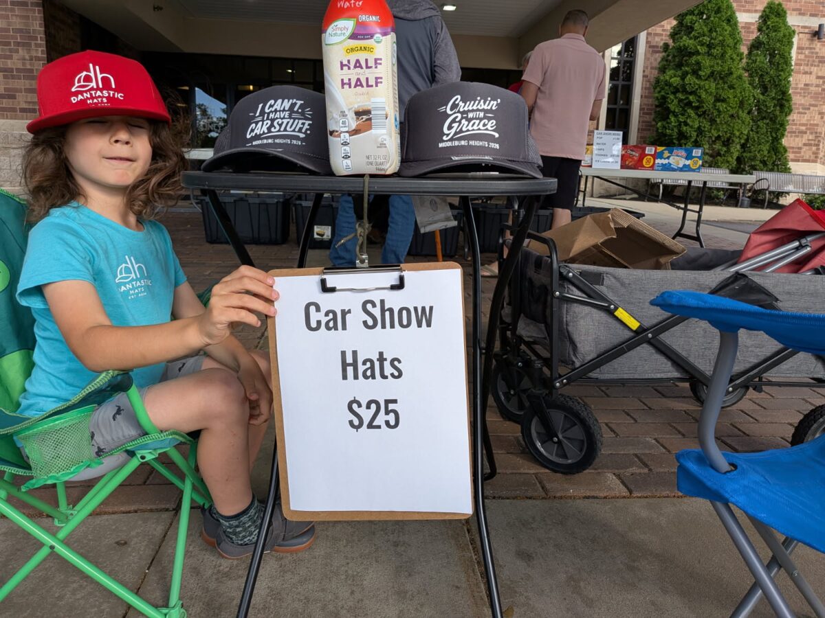 Daniel at his Dantastic Hats booth with custom Middleburg Heights 2026 car-show hats and a 'Car Show Hats $25' sign.
